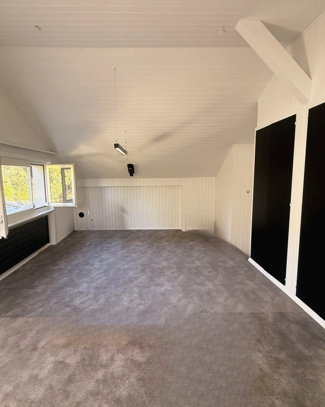 Combles à Fribourg, lambris peints en blanc mat, placards noirs et moquette grise, après les travaux